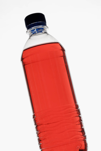 bottle of water with a red liquid in a glass on a white background - Foto, Imagem