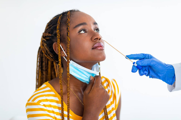 Verpleegkundige handen maken van PCR nasale test voor afro-Amerikaanse vrouw - Foto, afbeelding