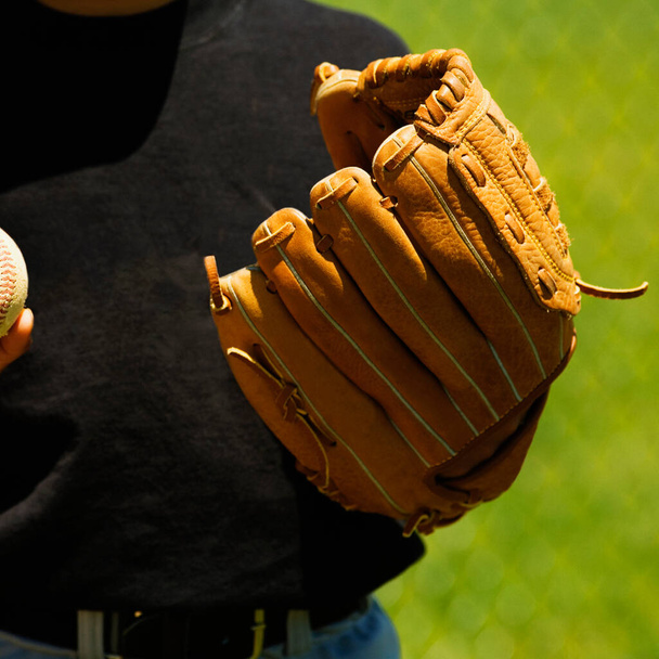 Mid section view of a baseball player wearing a baseball glove - Zdjęcie, obraz