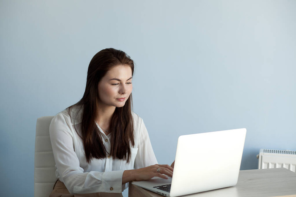 young beautiful girl in office clothes works on a laptop - Photo, image