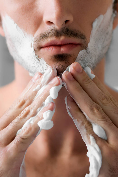 man shaving his face with a razor on a white background - Zdjęcie, obraz