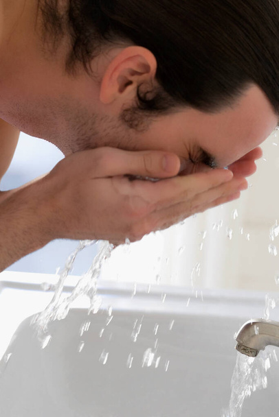 man washing his face with a glass of water - Foto, imagen