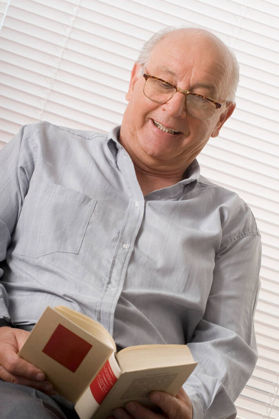senior man reading book at home - Fotó, kép