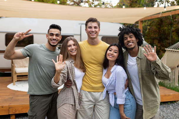 Портрет різноманітних молодих друзів, які позують і посміхаються на камеру біля трейлера, насолоджуючись осінніми вихідними під час поїздки на кемпінг
 - Фото, зображення