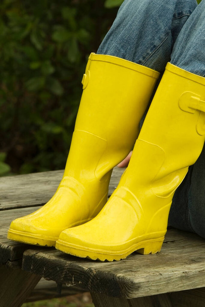 Low section view of a person wearing rubber boots - Foto, afbeelding