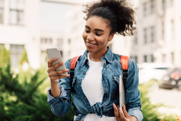 felice nero college ragazza utilizzando smartphone sms all'aperto - Foto, immagini