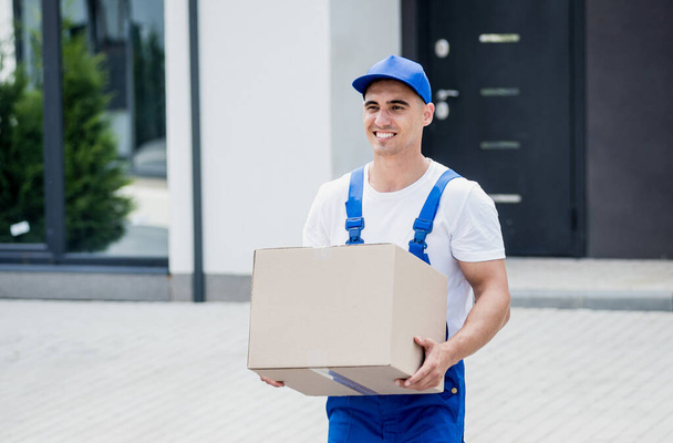 Young delivery man hold a cardboard box in his hands - Фото, зображення
