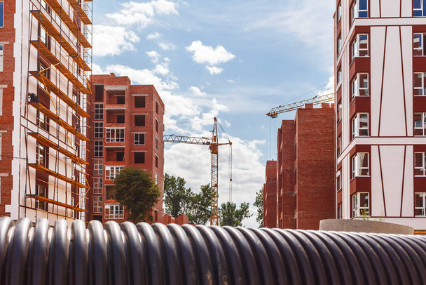Construction site with high-rise buildings with a plastic pipe in the foreground close up - 写真・画像