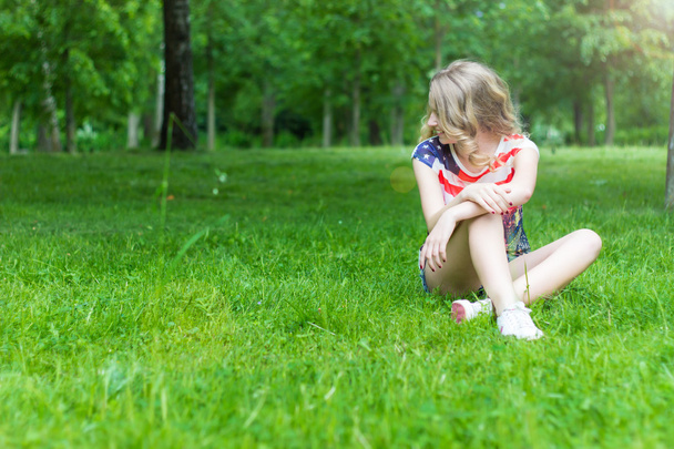 Nuori tyttö hymyilee ja onnellinen istuu nurmikolla kesällä Aurinkoinen päivä
 - Valokuva, kuva