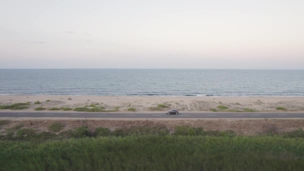 Widok z boku Podróżników samochód jazdy na wybrzeżu rano. - Materiał filmowy, wideo