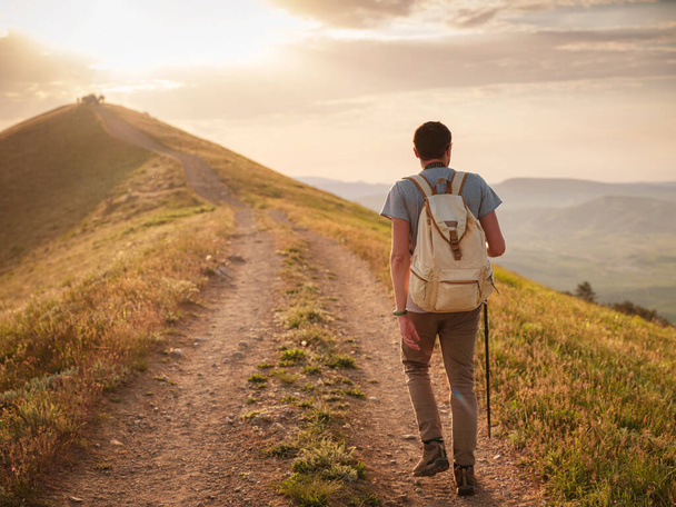 Fiatalember utazik egyedül séta az úton, és élvezi a kilátás nyílik a hegyekre és a tengeri táj naplementekor, az életmód koncepció az utazás szabadban. - Fotó, kép
