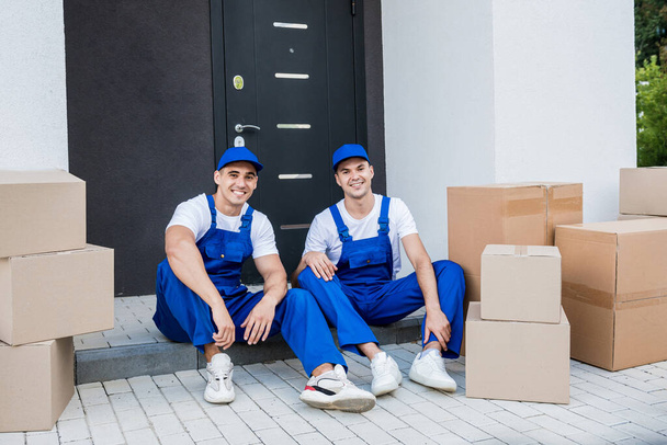 Two removal company workers have a break while sitting on the step - Fotó, kép