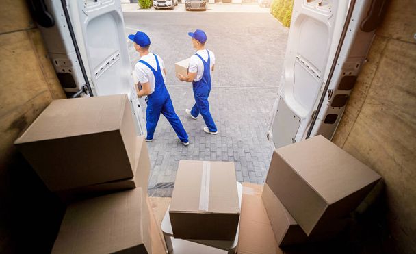 Two removal company workers unloading boxes from minibus - Foto, Imagen