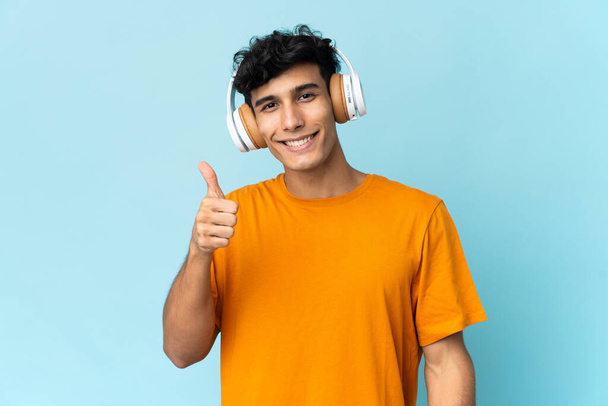Νεαρός Αργεντίνος απομονωμένος στο παρασκήνιο ακούγοντας μουσική και με τον αντίχειρα ψηλά - Φωτογραφία, εικόνα