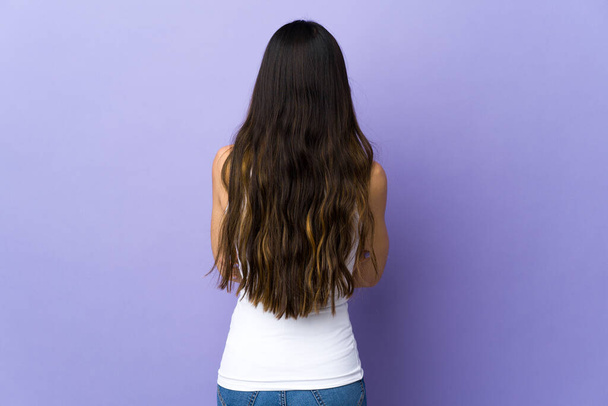 Junge brünette Frau über isolierten lila Hintergrund in Rückenlage - Foto, Bild