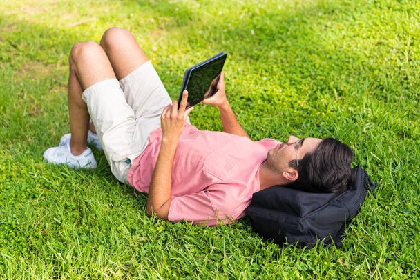 Junger Kaukasier im Freien in einem Park mit einem Tablet - Foto, Bild