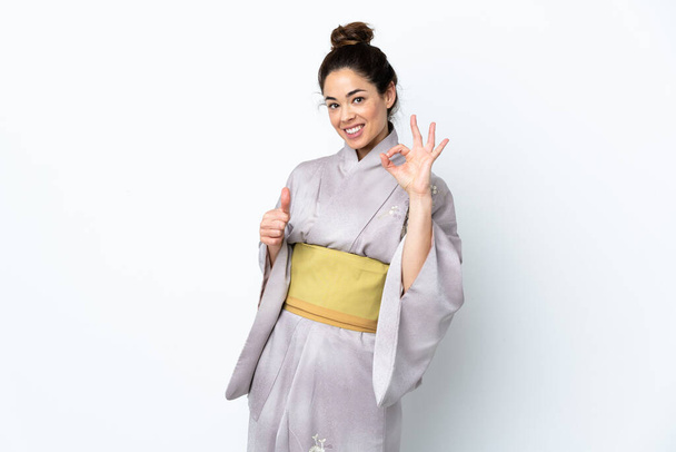 Kobieta w kimono na odosobnionym tle pokazuje znak ok i kciuk w górę gest - Zdjęcie, obraz