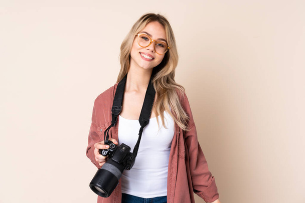 Young photographer girl over isolated background with glasses and smiling - 写真・画像
