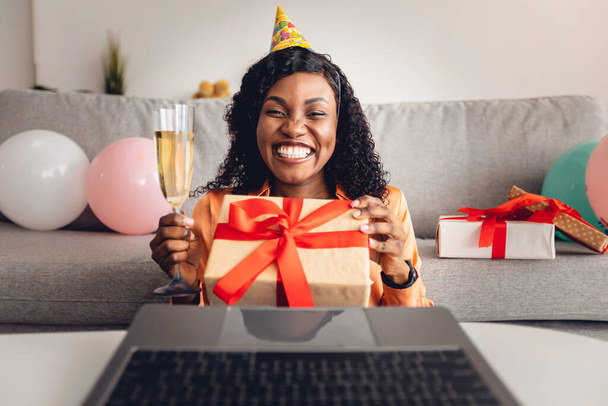 Front-View Of Black Woman Offering Birthday Gift To Laptop Indoors - Φωτογραφία, εικόνα
