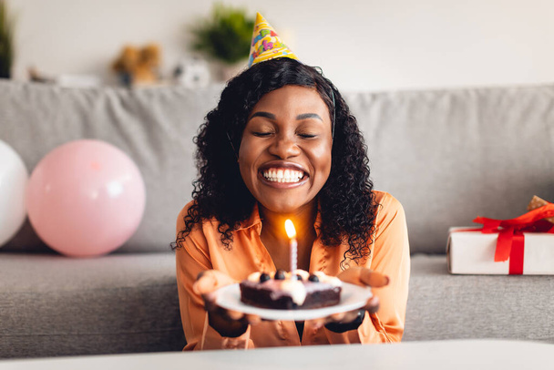 Mujer negra haciendo deseo soplando vela en pastel de cumpleaños interior - Foto, Imagen