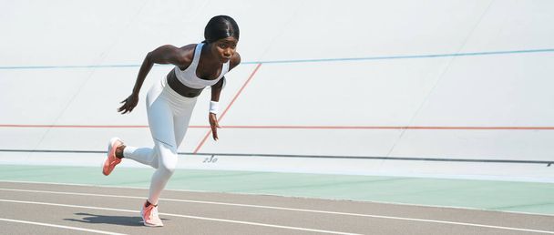 Confident young African woman in sports clothing running on track outdoors - Foto, Imagem