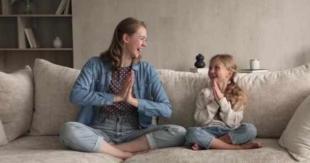 Mom her little daughter meditating sit cross-legged on sofa - Filmagem, Vídeo