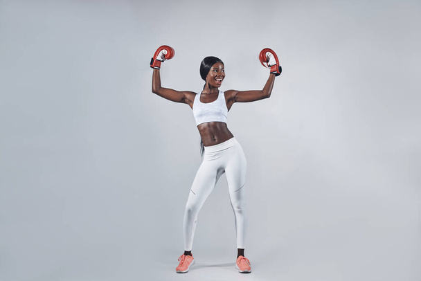 Beautiful young African woman in boxing gloves keeping arms raised - Valokuva, kuva