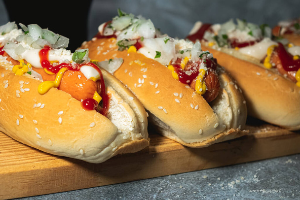 Close up of two hot dogs with sauces and on the bread has sesame seeds - Foto, Imagen