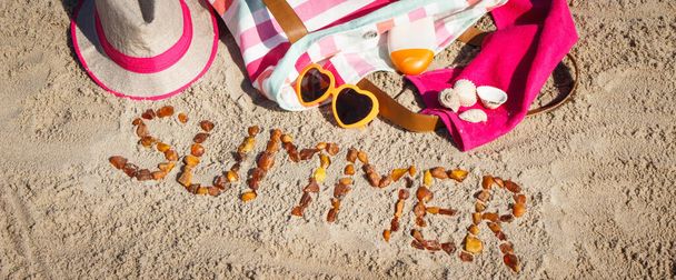 ビーチで砂の上でリラックスしたり日光浴のための琥珀色の石やアクセサリーで作られた碑文の夏。旅行、観光、休暇の時間の概念 - 写真・画像