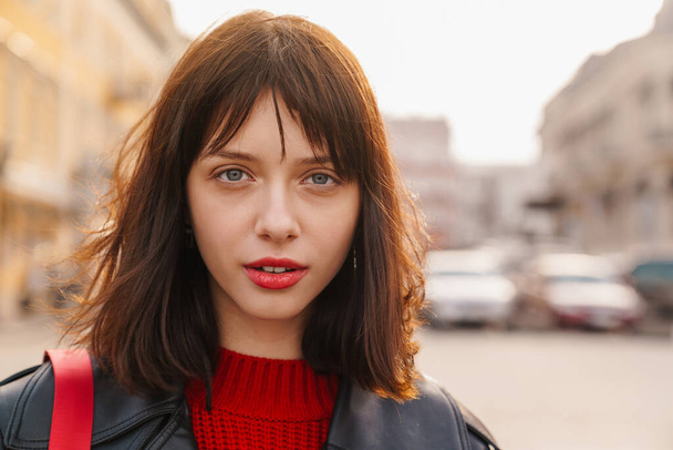 Close up of a young stylish brunette white woman with short hair standing on a street look at camera - Фото, зображення