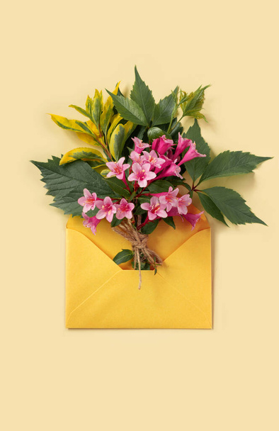 Greeting card with envelope and pink weigela flowers for mother's day or birthday. Creative design with copy space for text. - Фото, изображение