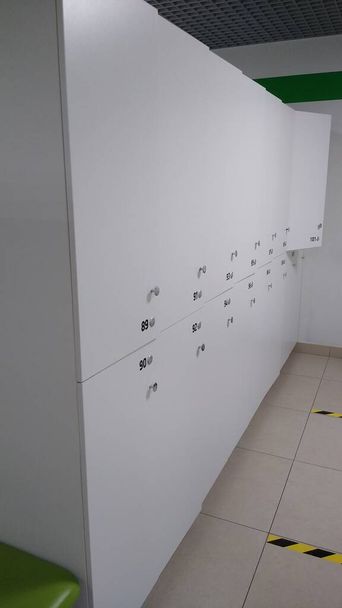 Шкафчики в раздевалке двух ярусов серого цвета с номерами - Фото, изображение