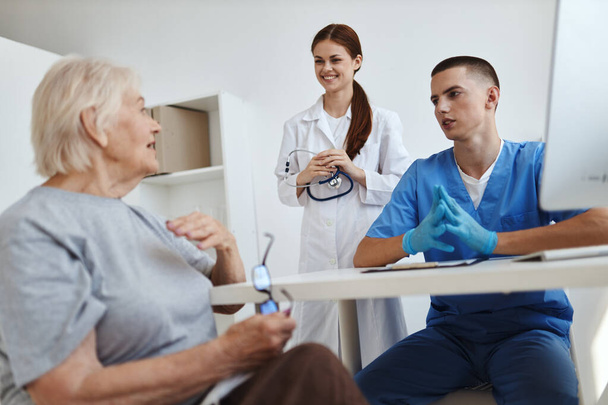 una enfermera y un médico hablando con una paciente anciana en un hospital - Foto, Imagen