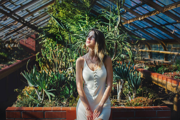 young woman in a white dress in a greenhouse with succulents - Photo, Image