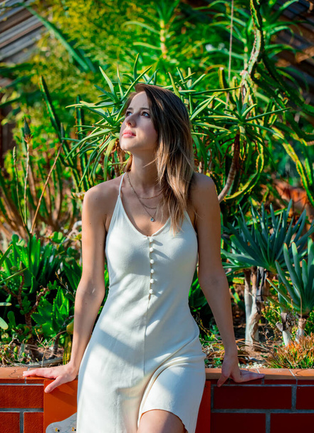 mujer joven en un vestido blanco en un invernadero con suculentas - Foto, Imagen