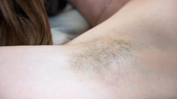 Close up shot of woman armpit with growing hair, woman lying on salon couch prepared for wax depilation procedure. Modern trend of natural beauty, growing hair under the armpits - Footage, Video