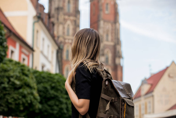 молодая девушка с рюкзаком на фоне старой церкви в Европе - Фото, изображение