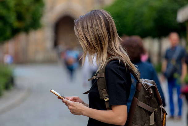 νεαρή κοπέλα με ένα smartphone στο παρασκήνιο της παλιάς εκκλησίας στην Ευρώπη - Φωτογραφία, εικόνα