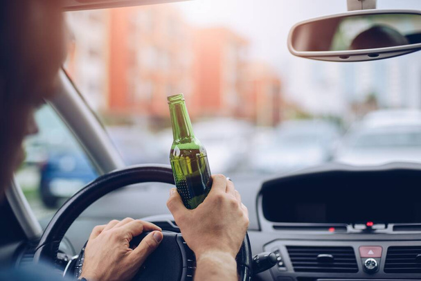 Μεθυσμένος ενήλικας οδηγεί ένα αμάξι με ένα μπουκάλι μπύρα.. - Φωτογραφία, εικόνα