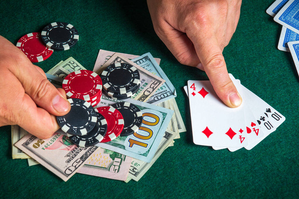 Il giocatore punta con il dito ad una combinazione vincente di due coppie nel gioco del poker su un tavolo con fiches e denaro in un casinò - Foto, immagini