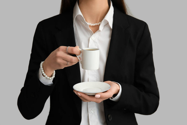 Woman drinking tasty coffee on grey background, closeup - Foto, afbeelding