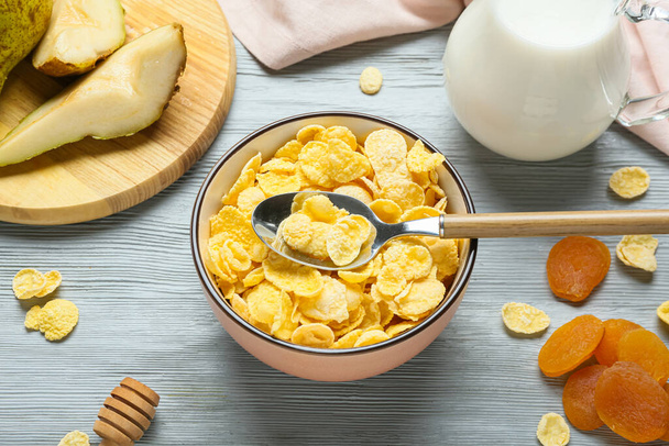 Bowl with tasty cornflakes on color wooden background - Zdjęcie, obraz
