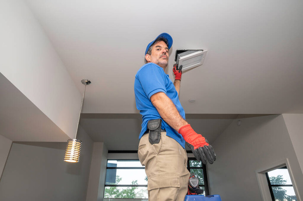 HVAC technician working on a ceiling vent - Photo, Image