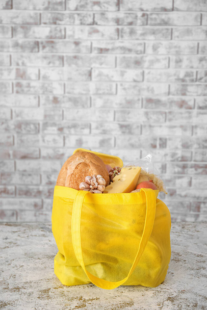 Эко-сумка с различными продуктами на светлом фоне брика - Фото, изображение