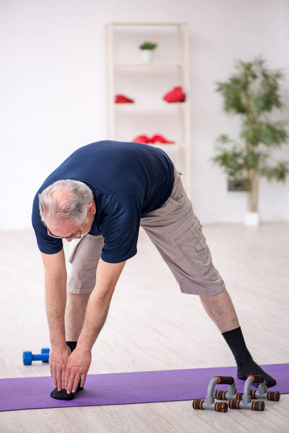Старик занимается спортом в помещении - Фото, изображение