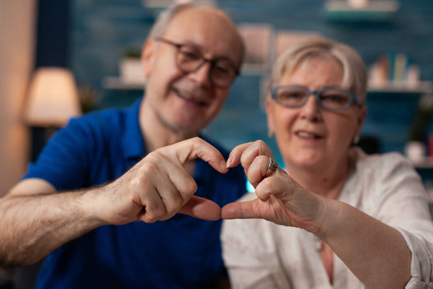 Porträt eines Mannes und einer Frau im Ruhestand, die Hände in Herzform halten - Foto, Bild