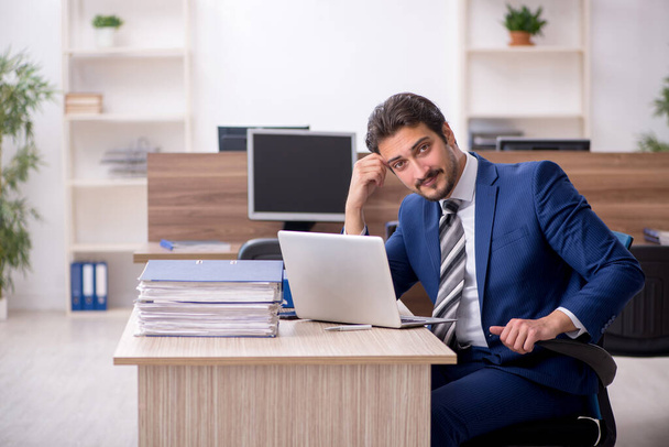 Jeune employé masculin et trop de travail au bureau - Photo, image