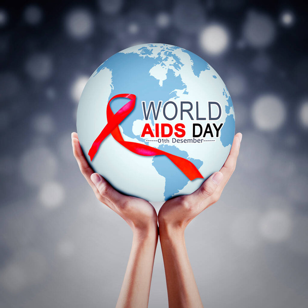 Mãos desconhecidas segurando um globo terrestre com fita vermelha e texto do Dia Mundial da Aids em fundo de luz turva - Foto, Imagem