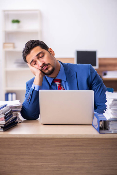 Young male employee unhappy with excessive work at workplace - Foto, Imagen