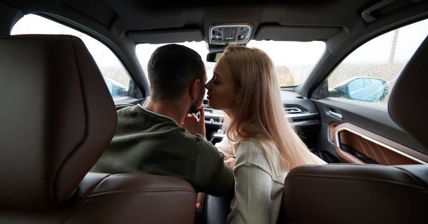Glückliche Männer und Frauen, die im Auto unterwegs sind. Schönes junges Paar auf dem Beifahrersitz, gutaussehender Mann am Steuer eines komfortablen Autos. Frau küsst Fahrerin. - Foto, Bild